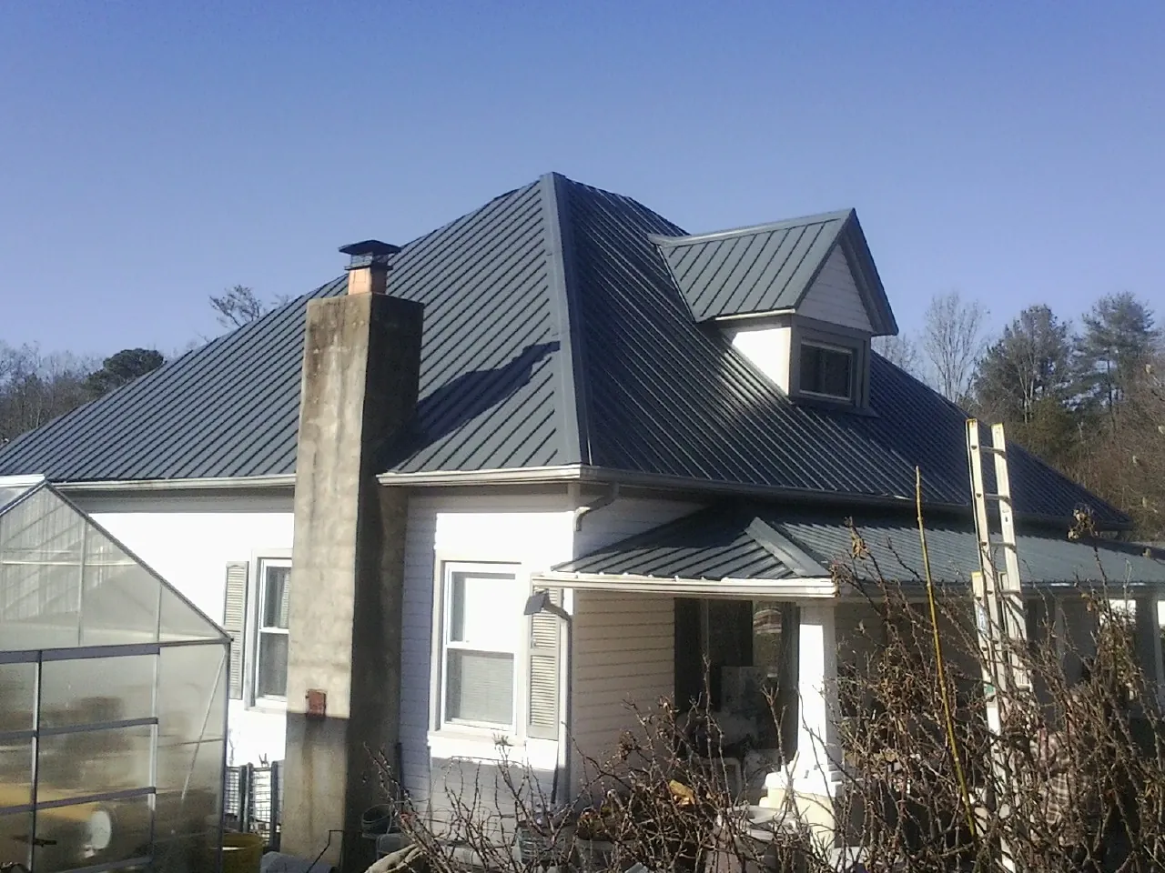 Dark blue standing seam metal roof on a white farmhouse with dormer — Slate & Tile Roof Repair by Roofing Brothers in Lenni
