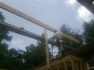 Carpenter setting a ridge beam over a new addition frame — Ice Dam Removal by Roofing Brothers in Lenni