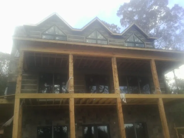 Dormers and porch framing on a large log home under construction — Roof Coating work by our crew in Lenni