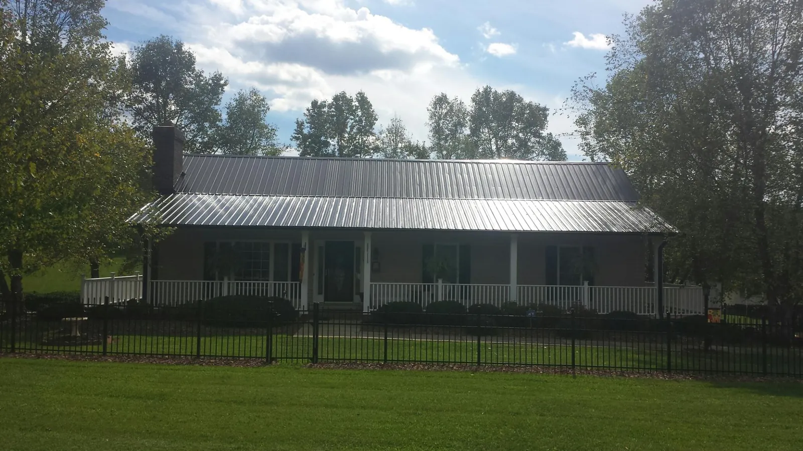 Gray metal roof on a brick ranch with a full width front porch — Gutter Guard Installation work by our crew in Lenni