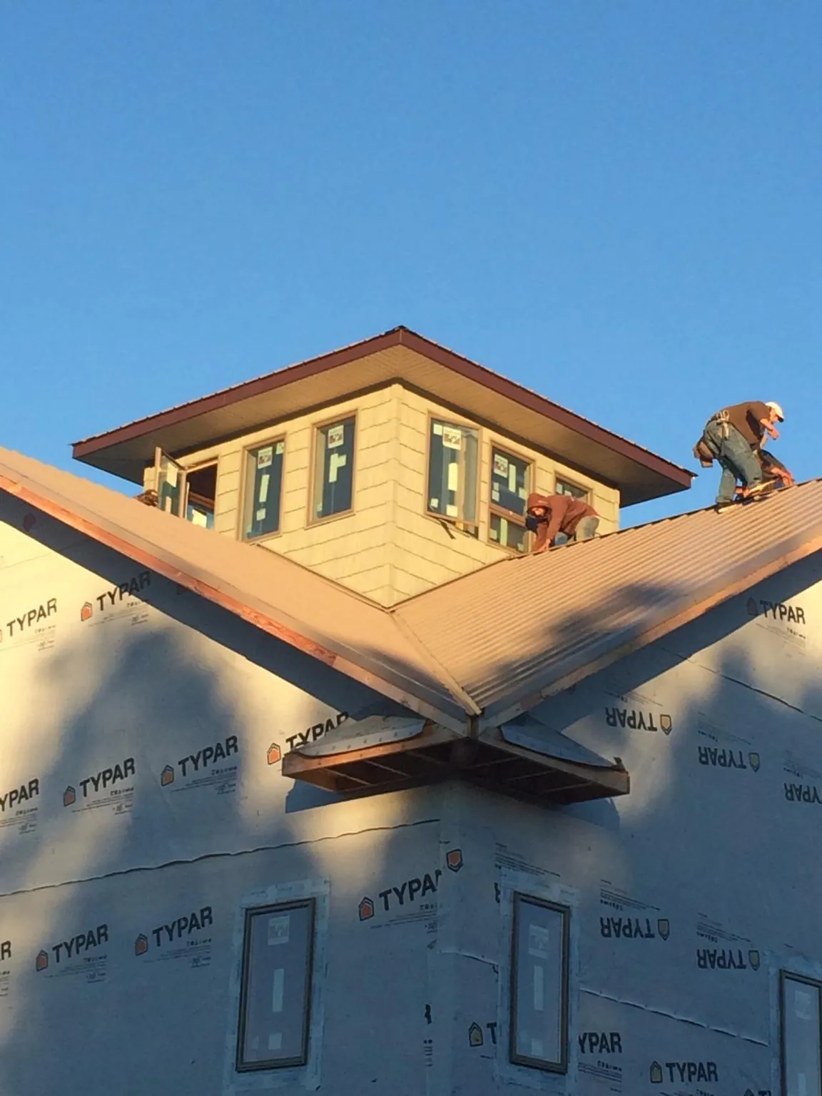 Roofers working around a rooftop cupola on a new metal roof at sunset — Roof Waterproofing in Lenni by Roofing Brothers